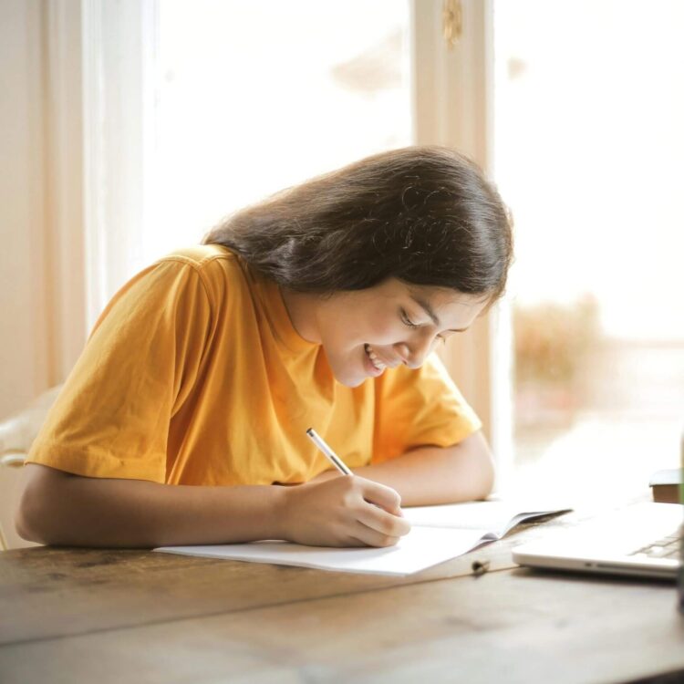 Student writing and smiling