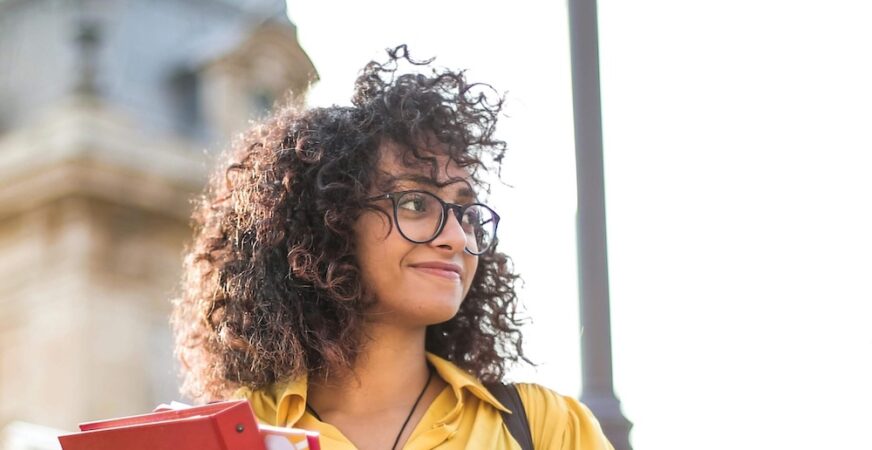 A girl holding books and looking into the distance